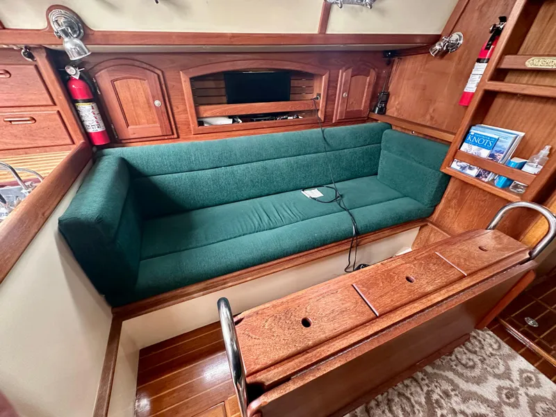 Slide: The Image of Interior of 1998 Pacific Seacraft Cutter with green sofa and wooden cabinetry. - 13