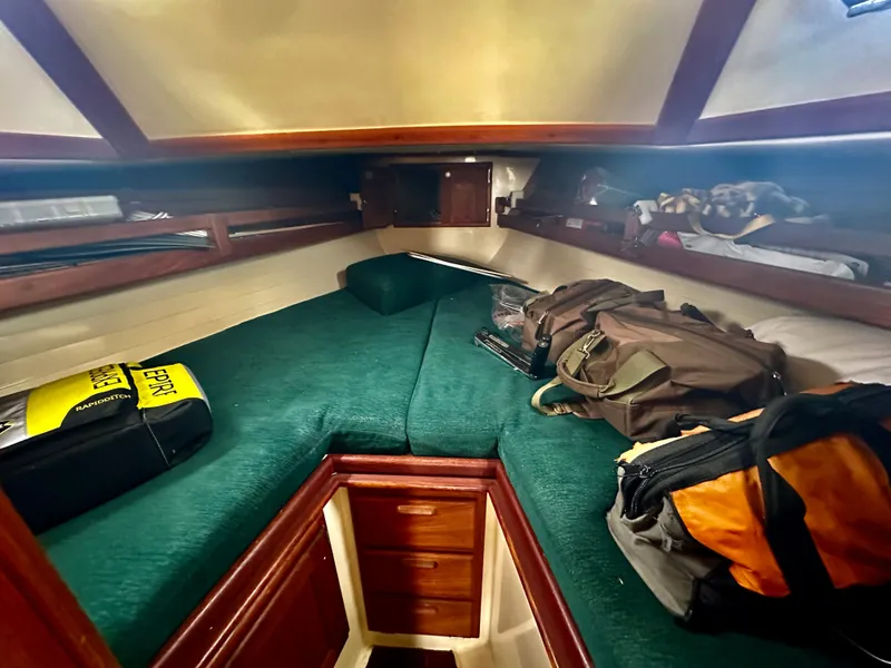 Slide: The Image of 1998 Pacific Seacraft Cutter cabin interior with green bedding and storage space. - 15