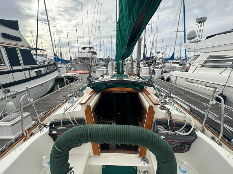 Slide: The Image of 1998 Pacific Seacraft Cutter sailboat docked in a marina, surrounded by other boats. - 22