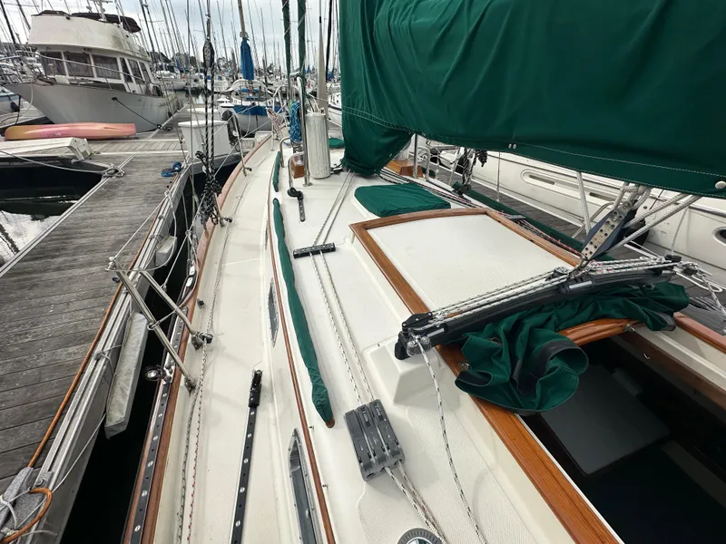 Slide: The Image of 1998 Pacific Seacraft Cutter sailboat docked, featuring green sail covers and wooden trim. - 23