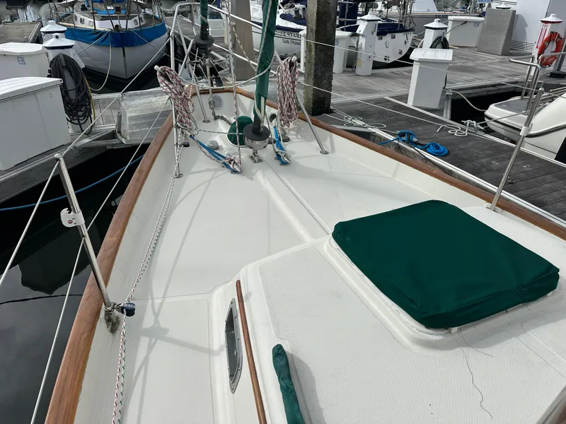 Slide: The Image of 1998 Pacific Seacraft Cutter sailboat deck at marina, featuring green covers and wooden trim. - 25