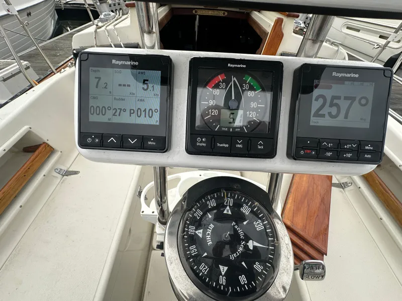 Slide: The Image of Cockpit instruments of a 1998 Pacific Seacraft Cutter sailboat, featuring Raymarine displays and compass. - 7