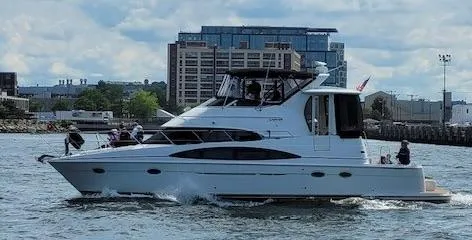 Slide: The Image of 2002 Carver 444 Cockpit Motor Yacht cruising on water near urban backdrop. - 2
