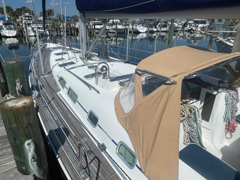 Slide: The Image of 2004 Beneteau Oceanis 473 sailboat docked at a marina, featuring a beige canopy. - 1