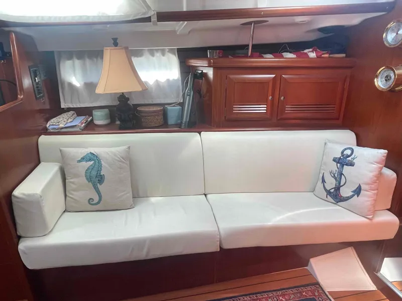 Slide: The Image of Interior of 2004 Beneteau Oceanis 473 yacht with white sofa and nautical-themed pillows. - 16