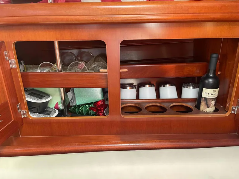 Slide: The Image of Wooden cabinet interior on a 2004 Beneteau Oceanis 473, featuring glasses and a wine bottle. - 17