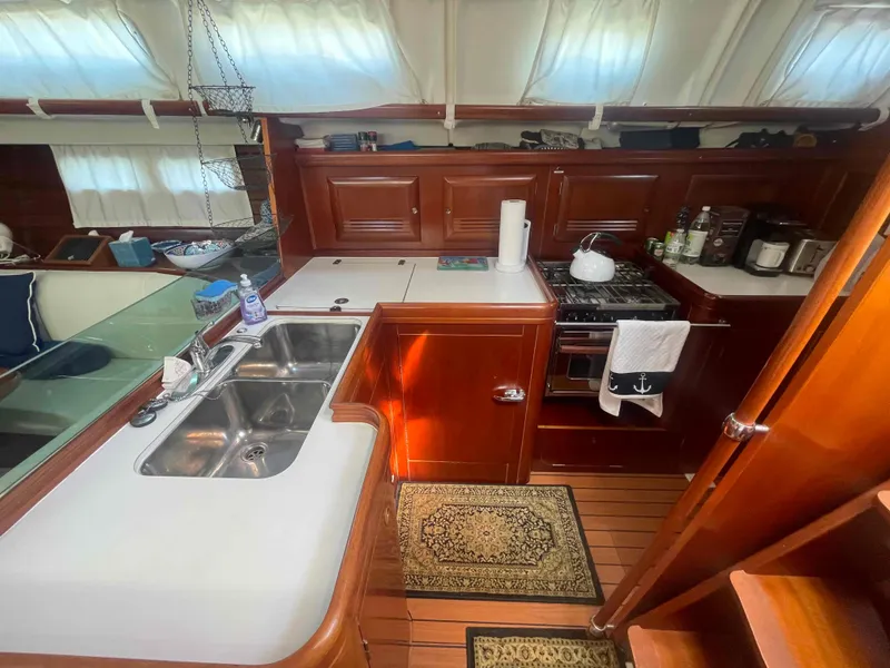 Slide: The Image of Interior of 2004 Beneteau Oceanis 473 yacht kitchen with wooden cabinetry and dual sink. - 20