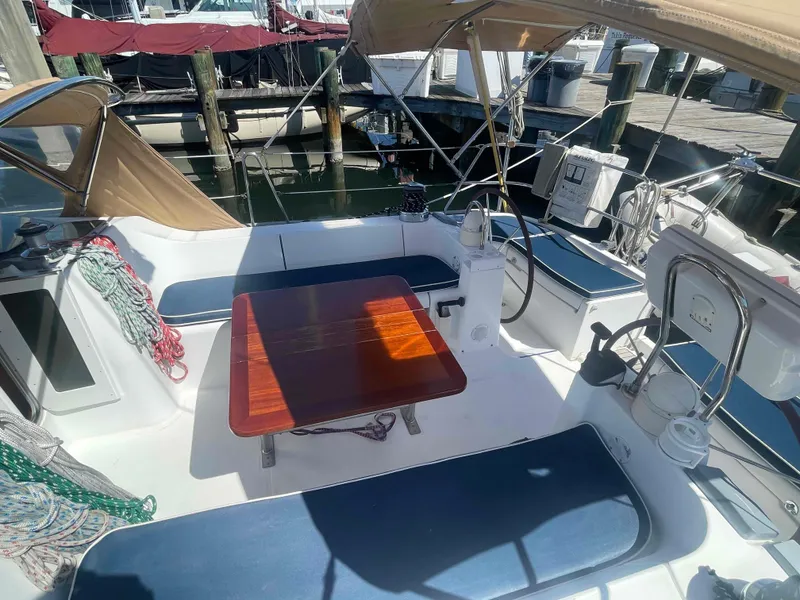 Slide: The Image of 2004 Beneteau Oceanis 473 sailboat cockpit with seating, table, and canopy in marina. - 45