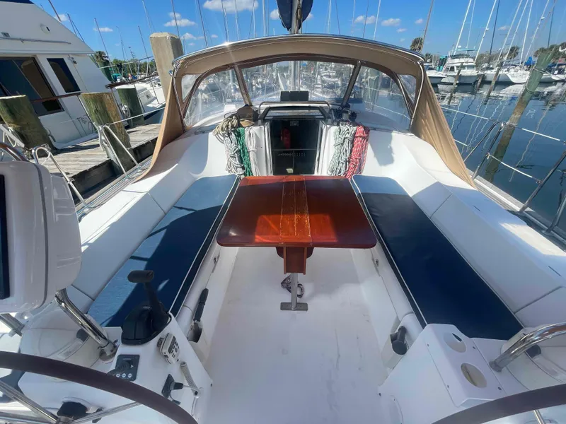 Slide: The Image of 2004 Beneteau Oceanis 473 sailboat cockpit with seating and table, docked at marina. - 47