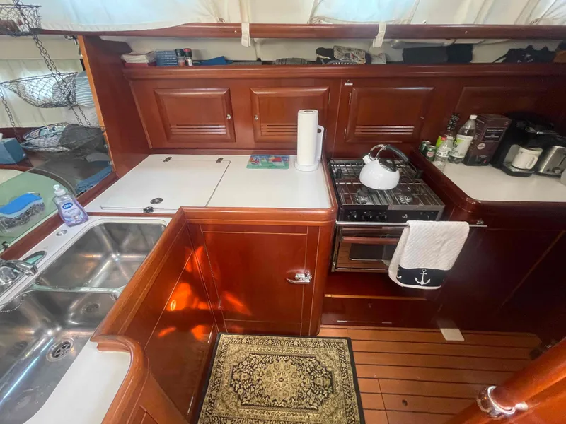 Slide: The Image of Galley kitchen in 2004 Beneteau Oceanis 473 sailboat with wood cabinetry and modern appliances. - 5