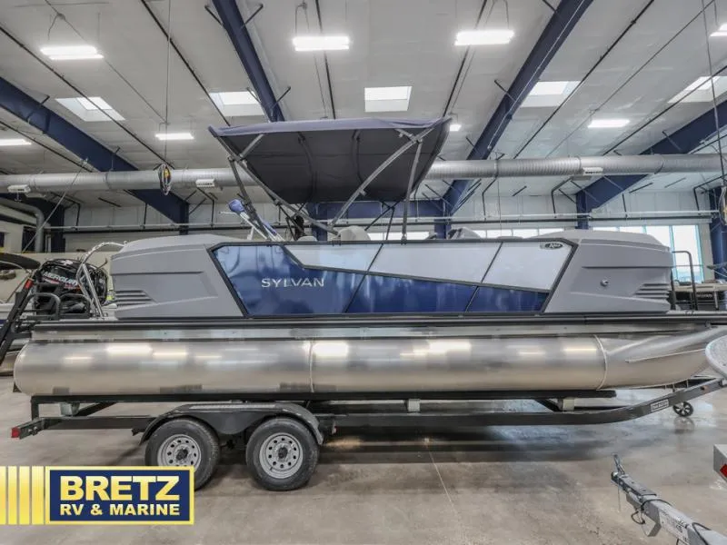 Slide: The Image of Pontoon boat in showroom, Sylvan brand, on trailer, Bretz RV & Marine logo visible. - 3