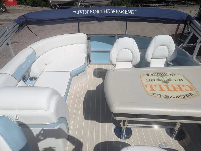 Slide: The Image of 2025 Berkshire 22E CTS boat interior with seating and table, featuring "Livin' for the Weekend" canopy. - 4