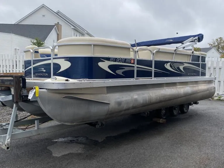 The Image of 2011 Bennington 22SLi pontoon boat on trailer, parked outdoors. - 0