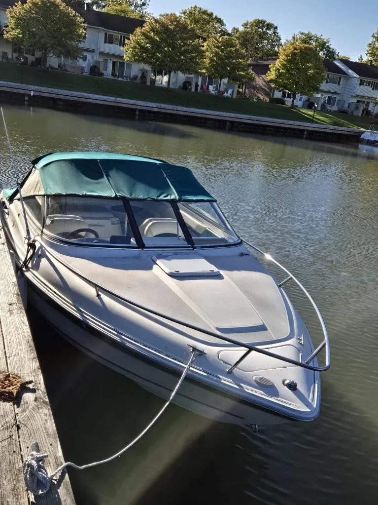 The Image of 1998 Wellcraft Eclipse 2000SC boat docked on calm water, surrounded by trees and houses. - 0