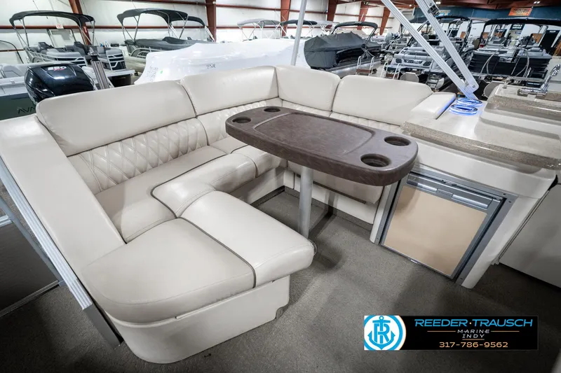 Slide: The Image of 2014 Bennington 2250 RCB boat interior with beige seating and table in showroom. - 30