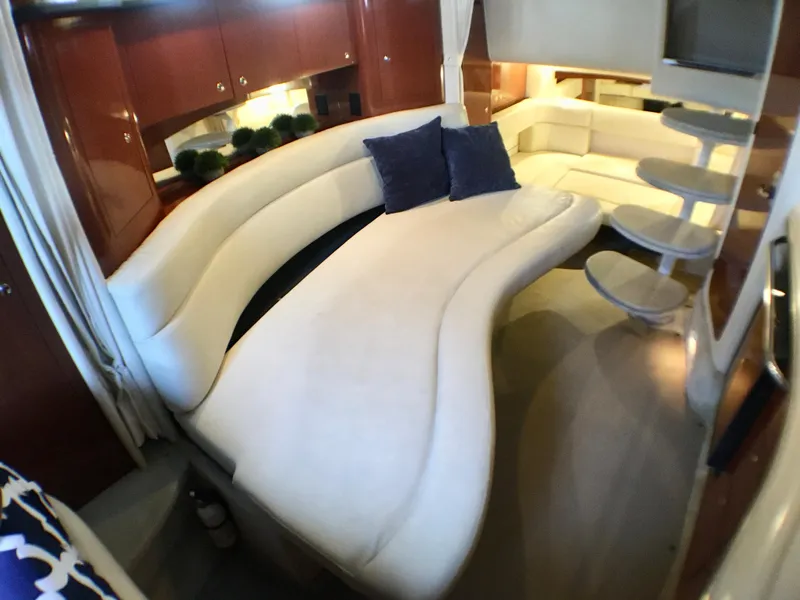 Slide: The Image of 2002 Sea Ray 320 Sundancer interior with curved white seating and blue cushions. - 23
