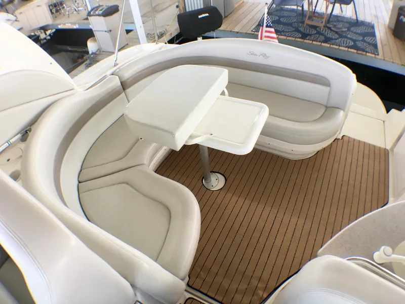 Slide: The Image of 2002 Sea Ray 320 Sundancer interior with curved seating and table on teak flooring. - 25