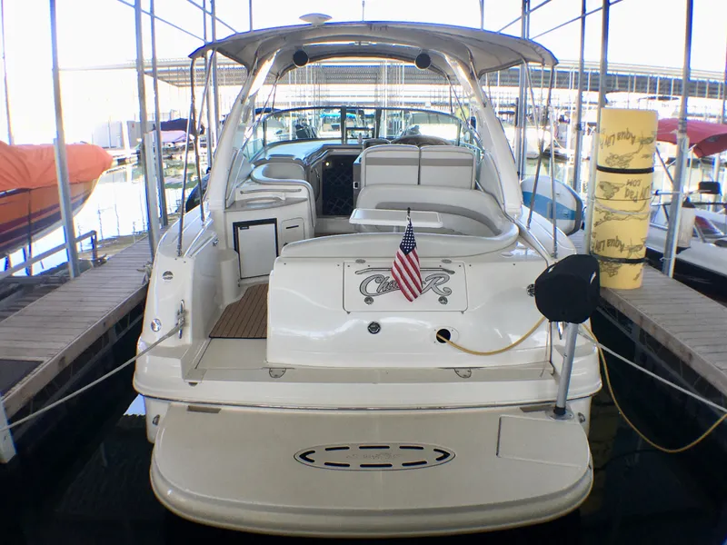 Slide: The Image of 2002 Sea Ray 320 Sundancer docked, rear view with American flag, in covered marina. - 3