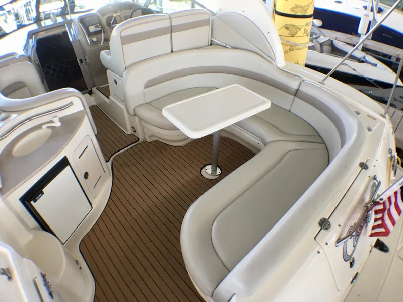 Slide: The Image of 2002 Sea Ray 320 Sundancer interior with curved seating and table on teak deck. - 6