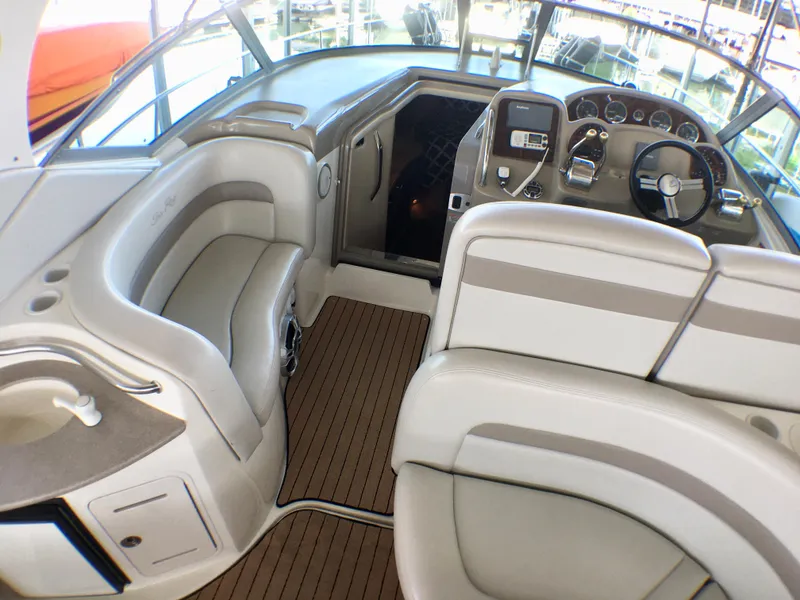 Slide: The Image of 2002 Sea Ray 320 Sundancer cockpit with beige seating and wooden flooring. - 7