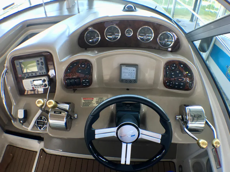 Slide: The Image of 2002 Sea Ray 320 Sundancer helm with gauges, steering wheel, and navigation controls. - 9