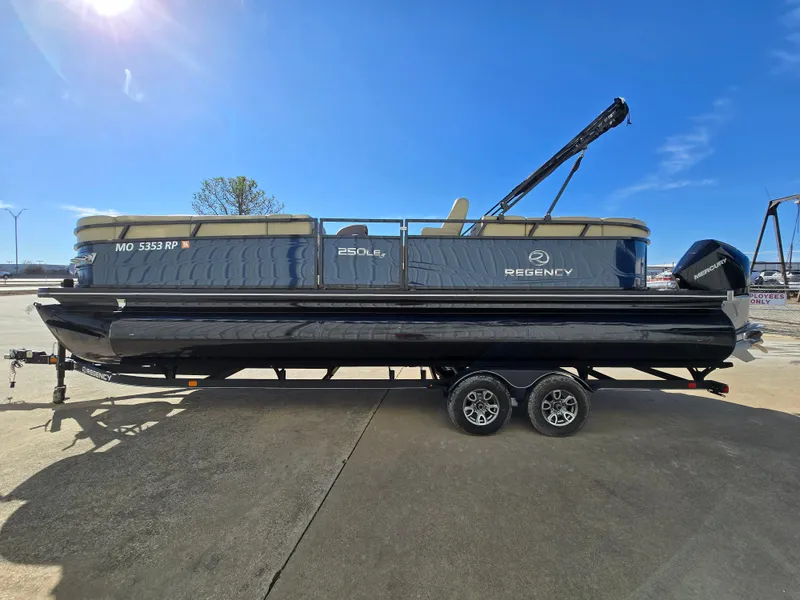 Slide: The Image of 2023 Regency 250 LE3 pontoon boat on trailer, sunny day, side view. - 2