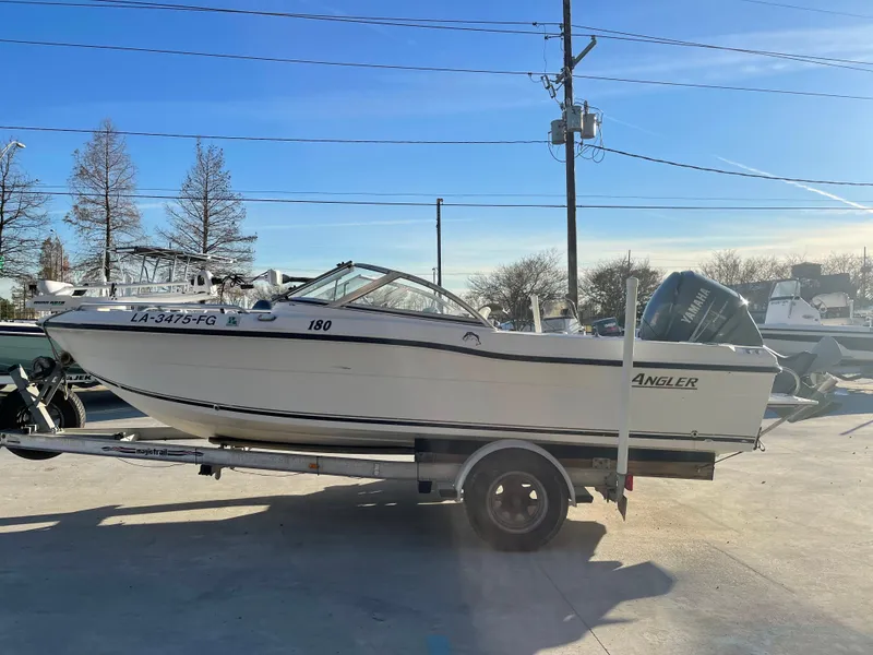 Slide: The Image of 2002 Angler 18 DC boat on trailer, parked outdoors under clear blue sky. - 4