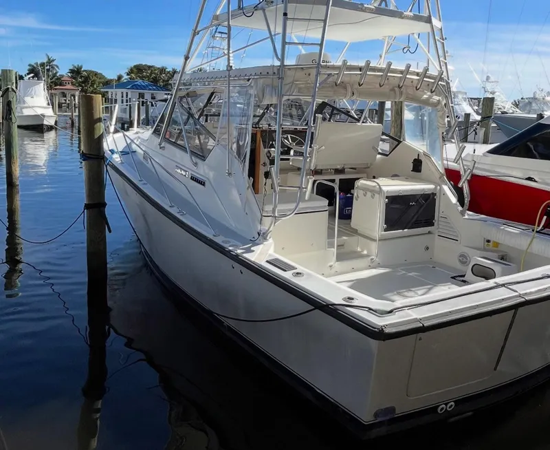 Slide: The Image of 1990 Rampage 36 Sportfisherman boat docked at marina, featuring spacious deck and fishing equipment. - 16