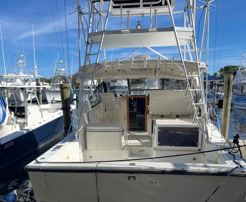 Slide: The Image of 1990 Rampage 36 Sportfisherman boat docked at marina, featuring spacious deck and fishing tower. - 4