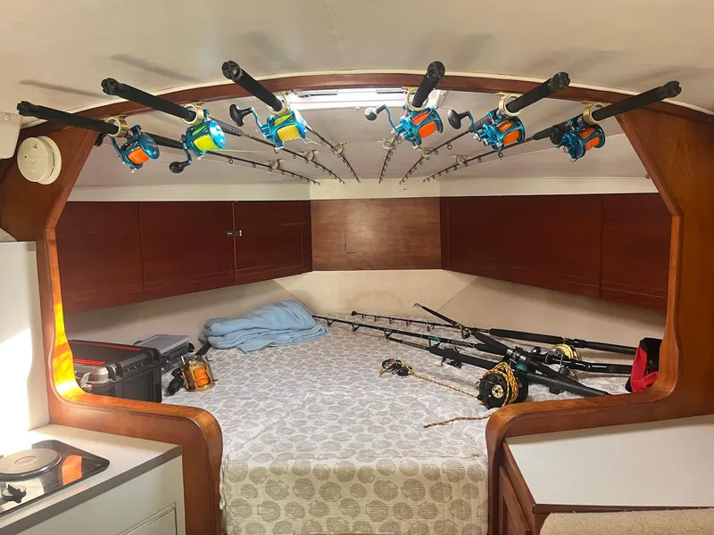 Slide: The Image of 1990 Rampage 36 Sportfisherman cabin with fishing rods and cozy bed setup. - 8