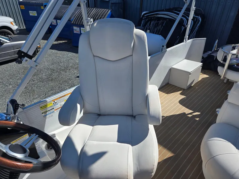 Slide: The Image of Captain's chair on 2016 AquaPatio 240 CB boat, featuring white upholstery and wooden deck. - 10