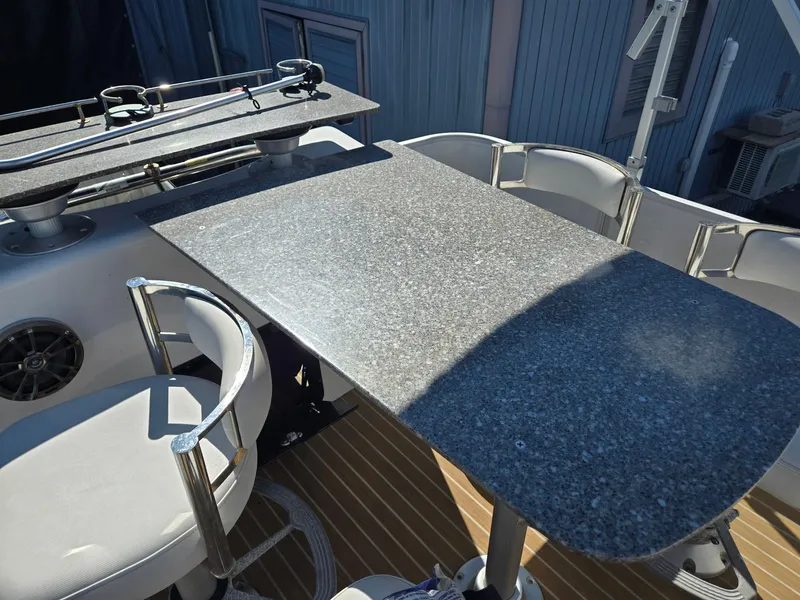 Slide: The Image of 2016 AquaPatio 240 CB boat interior with granite table and white seating. - 18