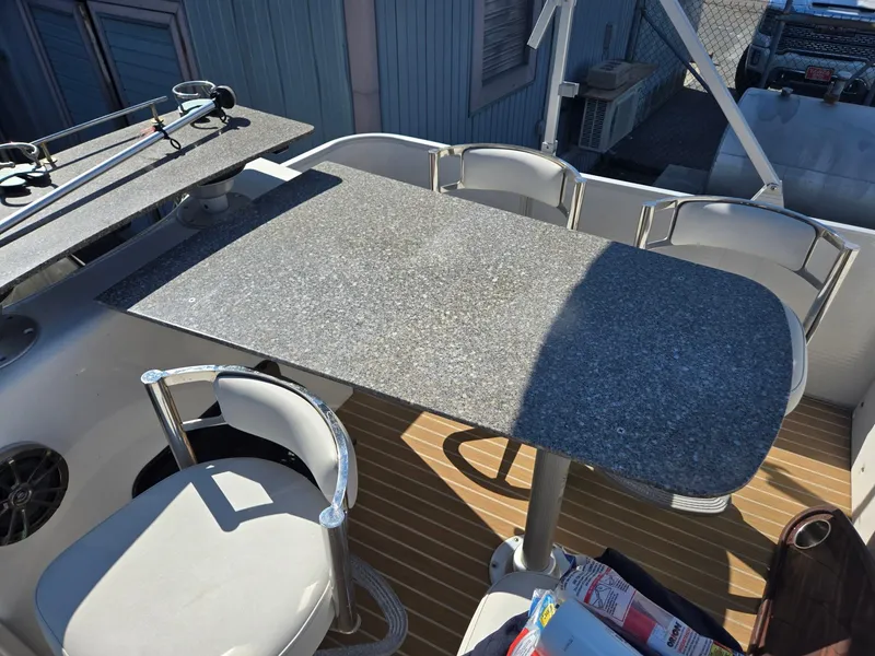Slide: The Image of 2016 AquaPatio 240 CB boat interior with granite table and white chairs. - 19