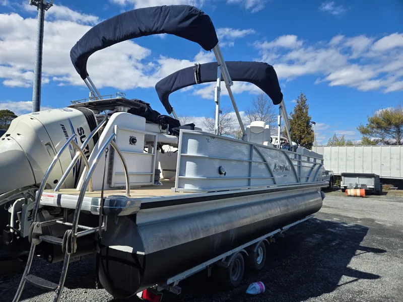 Slide: The Image of 2016 AquaPatio 240 CB pontoon boat with dual bimini tops, parked outdoors. - 5