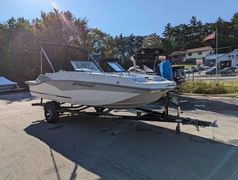 Slide: The Image of 2024 Starcraft SVX 210 IO boat on trailer in outdoor setting. - 0