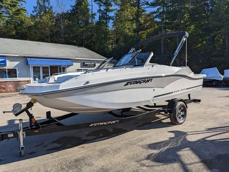 Slide: The Image of 2024 Starcraft SVX 210 IO boat on trailer, parked outdoors near a building. - 4
