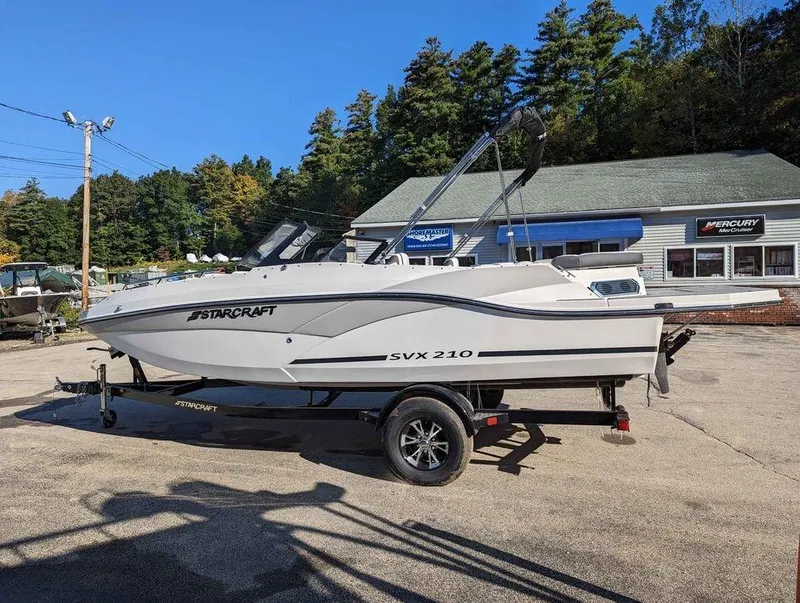 Slide: The Image of 2024 Starcraft SVX 210 IO boat on trailer, parked outdoors near dealership. - 9