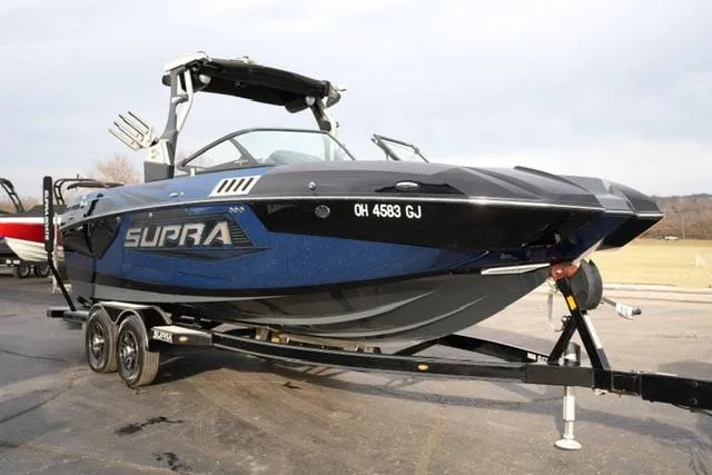 Slide: The Image of 2019 Supra SE 450 boat on trailer, black and blue design, parked outdoors. - 4