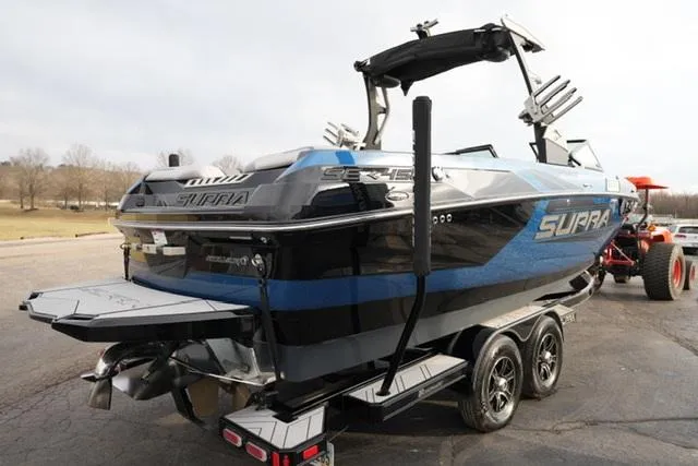 Slide: The Image of 2019 Supra SE 450 boat on trailer, blue and black design, parked outdoors. - 5