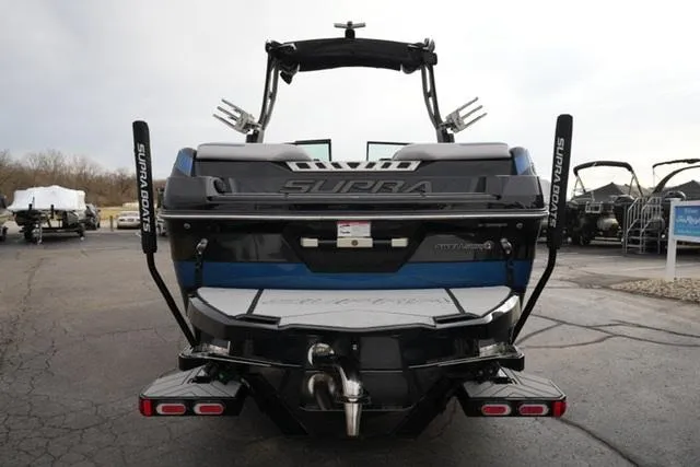 Slide: The Image of 2019 Supra SE 450 boat, rear view, parked on pavement, showcasing wakeboard tower and swim platform. - 6