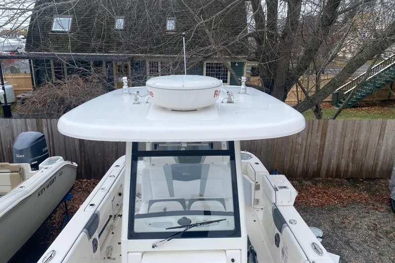 Slide: The Image of 2020 Robalo R272 Center Console boat with radar, parked near a wooden fence. - 38