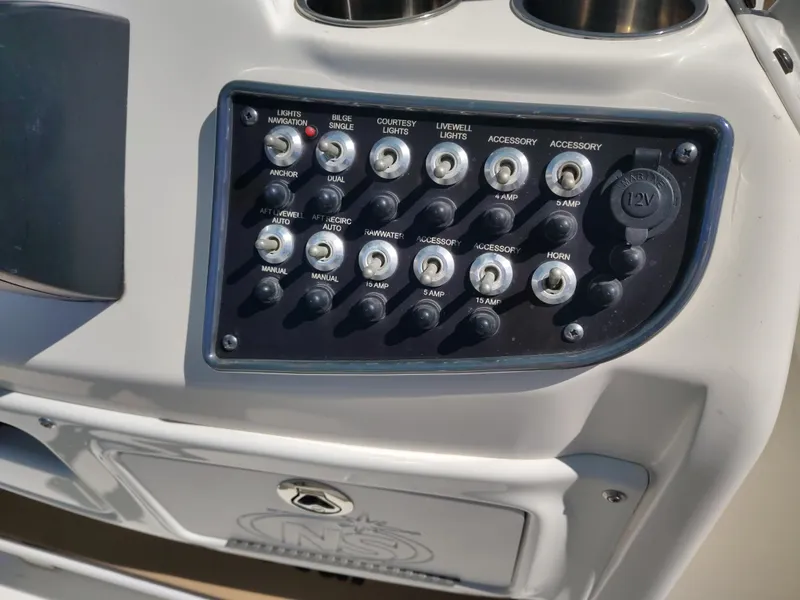 Slide: The Image of Control panel of 2021 NauticStar 2302 Legacy boat with various switches and 12V outlet. - 21