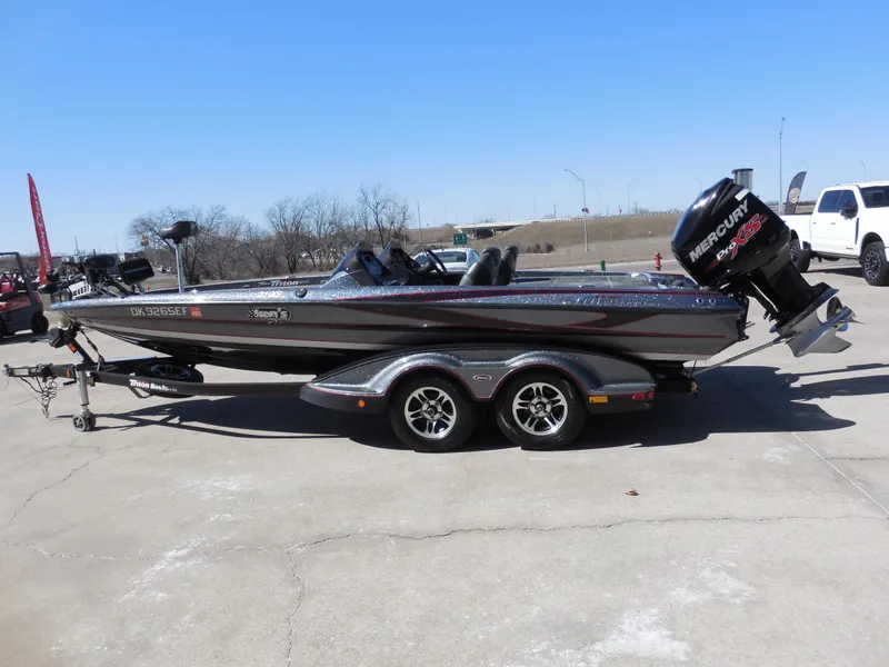 Slide: The Image of 2013 Triton 21XS DC boat with Mercury engine on a trailer, parked outdoors. - 5