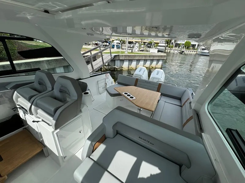 Slide: The Image of 2024 Beneteau Gran Turismo 32 yacht interior with seating and table, docked by the water. - 8