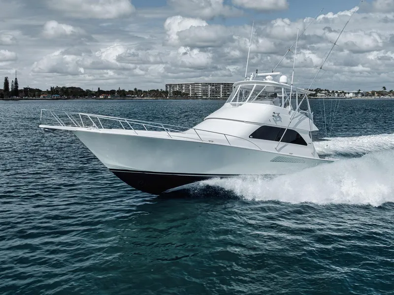 Slide: The Image of 2009 Viking 54 Convertible yacht cruising on open water under a cloudy sky. - 2