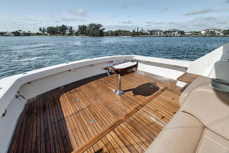 Slide: The Image of 2009 Viking 54 Convertible yacht with teak deck, overlooking serene waters and distant shoreline. - 27