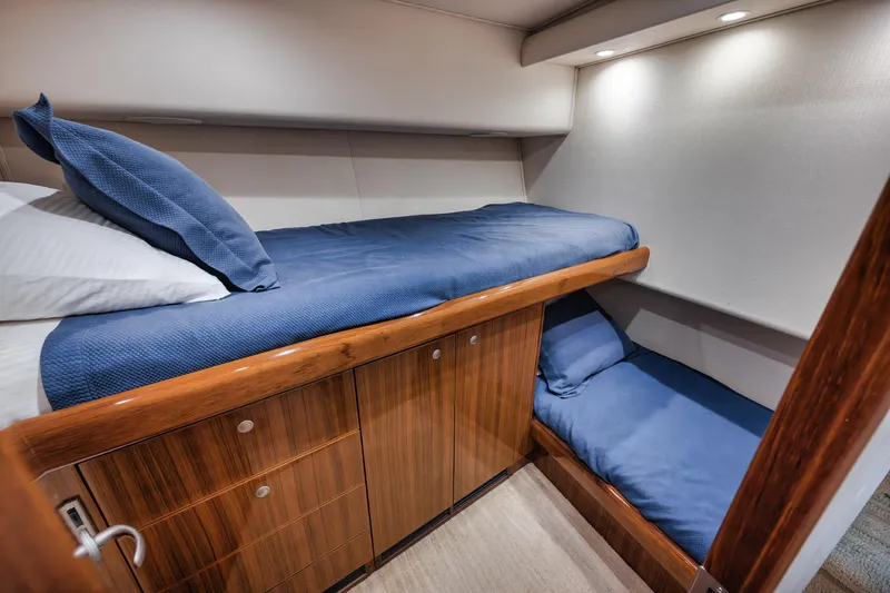 Slide: The Image of 2009 Viking 54 Convertible yacht cabin with wooden cabinetry and blue bedding. - 45