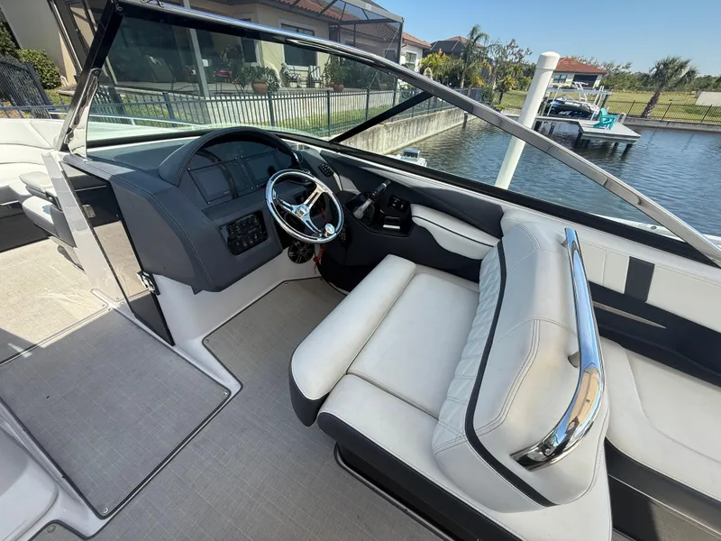 Slide: The Image of 2020 Regal 29 OBX boat interior with steering wheel and seating, docked by a canal. - 24