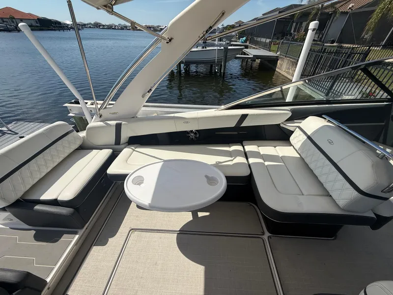 Slide: The Image of 2020 Regal 29 OBX boat interior with white seating and round table by the water. - 27
