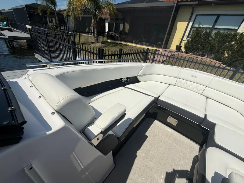 Slide: The Image of 2020 Regal 29 OBX boat with spacious white seating area, docked near waterfront homes. - 16